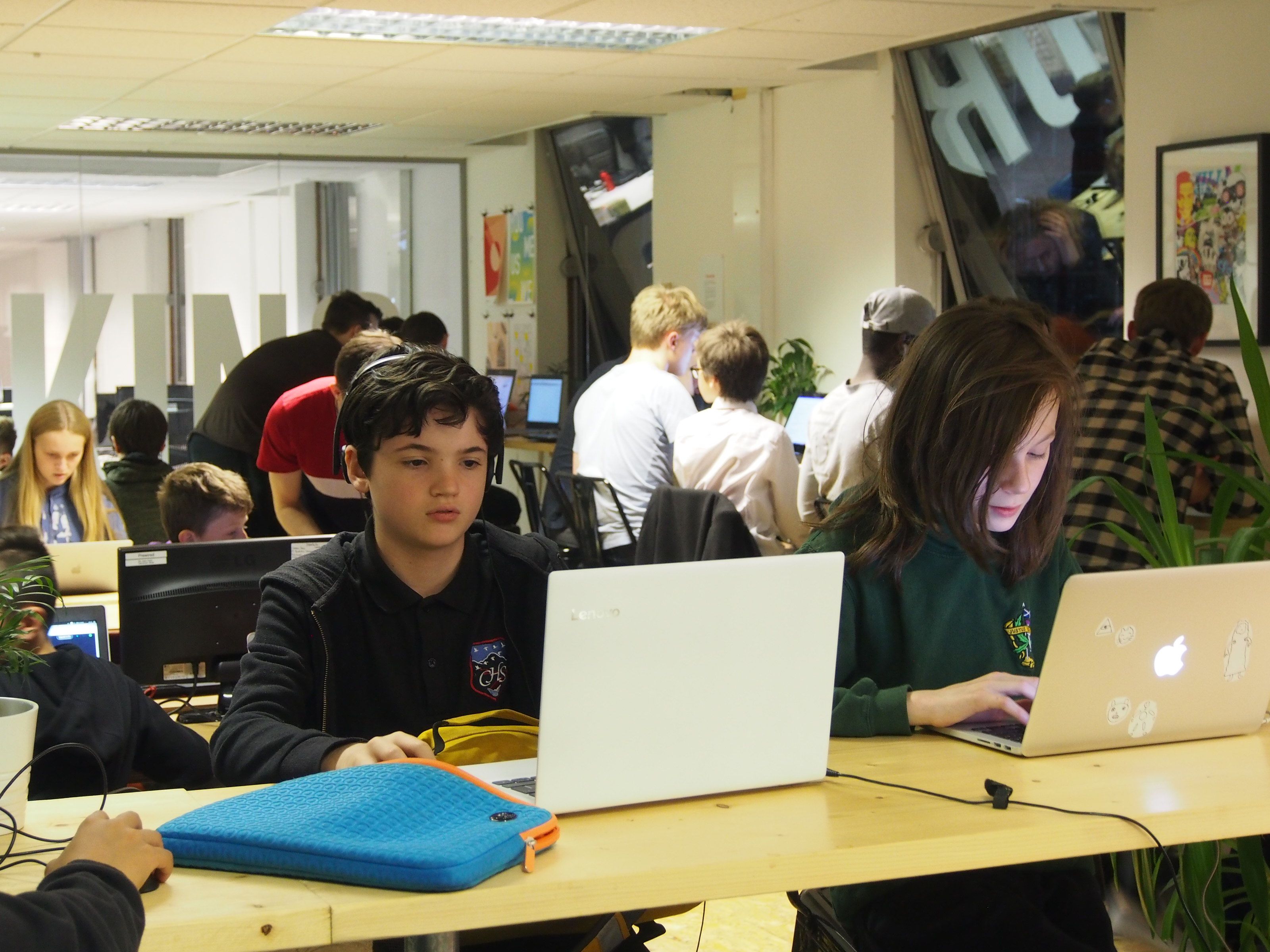 A room full of young people working on laptops at low and high tables